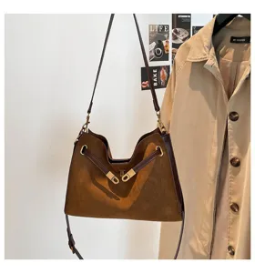 Vintage brown suede shoulder bag detail showing retro turn-lock hardware and strap.