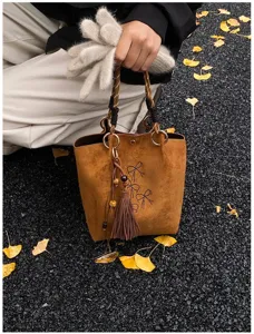 Damen Wildleder Eimer Tasche mit Strass Schleife, Quasten Anhänger und geflochtenem Griff.