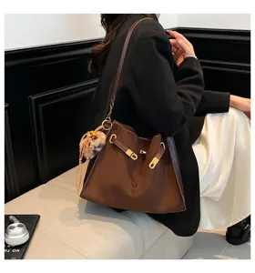 Detail view of brown suede tote bag with metal lock and cute furry charm for daily wear.