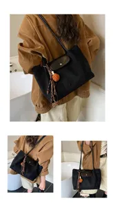 Korean style large capacity black shoulder bag with stylish tassel pendant and flap closure detail.