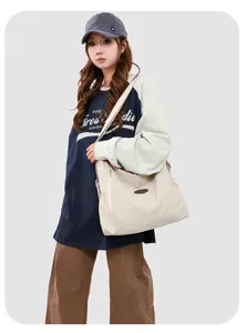 Detail view of a casual canvas shoulder bag worn by a model, showcasing its slouchy design.