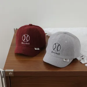 Detailed view of children corduroy baseball caps in wine red and gray colors with embroidery.