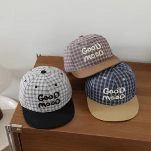 Vista detallada de gorras de béisbol de cuadros para niños con bordado y visiera plana.