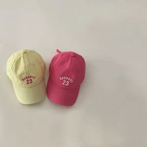 Detail view of kids lightweight breathable baseball caps in yellow and pink with embroidery.