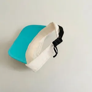 Close-up of kids summer sun visor hat strap buckle detail, turquoise brim and white band.