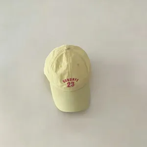 Detail shot of the yellow kids baseball cap featuring red embroidered goodbye 23 text design.