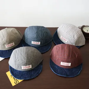 Detail shot of children's plaid baseball cap featuring a denim brim and front text label.