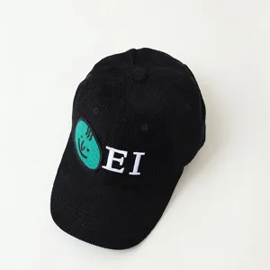 Detail view of a black corduroy baseball cap featuring an embroidered green face and white letters.