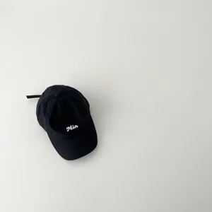 Detailed view of a black kids baseball cap featuring white embroidered letter Min on the front.