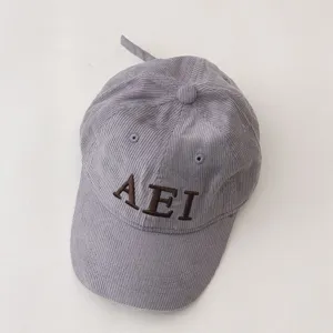 Close-up detail of gray corduroy children baseball cap with brown embroidered letters AEI.