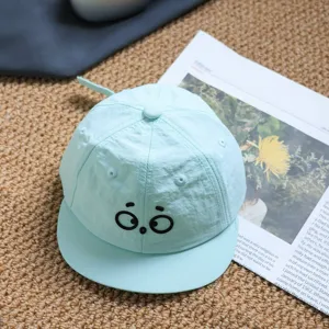 Close-up detail of cute cartoon eye embroidery kids baseball cap in mint green sun hat.
