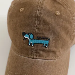 Close up view of brown corduroy kids baseball cap featuring cute blue dog embroidery design.