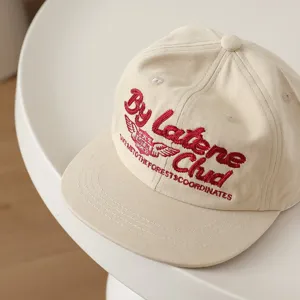 Gorra de béisbol beige para niños con bordado rojo y visera plana estilo hip-hop urbano.