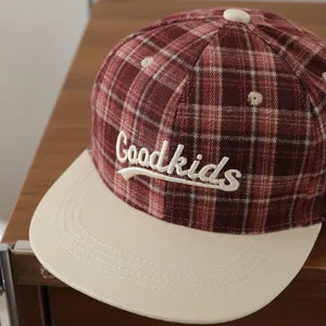 Vista detallada de gorra de cuadros para niños bordada con visera plana elegante.