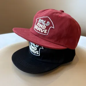 Primer plano de elegantes gorras de béisbol infantiles en rojo y negro con bordado.