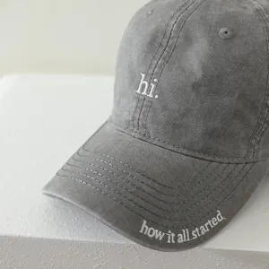 Grey washed cotton children baseball cap detail with white embroidery hi letter and brim text.