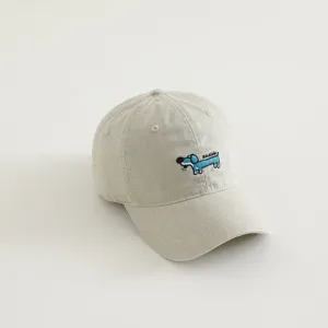 Detailed close-up view of the cute embroidered blue dog pattern on the beige cotton cap.