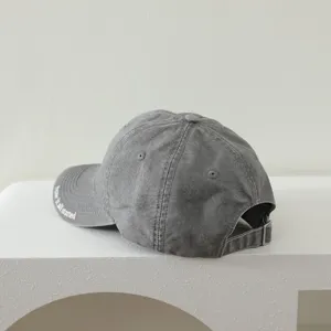 Close up detail of grey washed cotton baseball cap with back metal buckle and brim text.