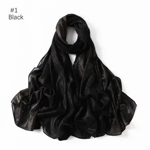 Close-up detail of black shimmering gold glitter chiffon hijab scarf, soft fabric texture.