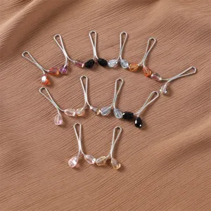 Detailed shot of sparkling crystal teardrop hijab pins, elegant metal U-shaped scarf clips.