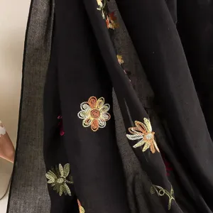 Closeup view of black cotton linen scarf featuring colorful embroidered floral patterns.