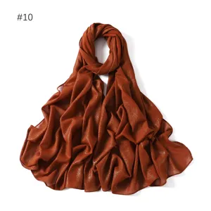 Detailed view of shimmering gold chiffon long scarf fabric texture and glitter effect.