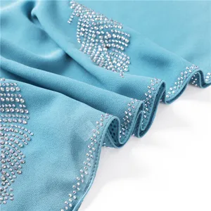 Close-up van blauwe chiffon hijab met schitterende strass bladpatroon details duidelijk.