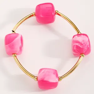 Detailaufnahme des eleganten Armbands mit rosa Harzperlen und goldenen Metallrohren.