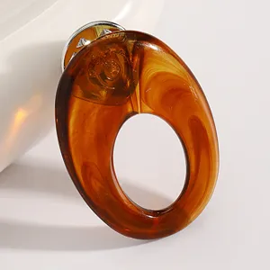 Gros plan détail de broche lunettes en acrylique écaille, montrant texture et fermoir métallique.
