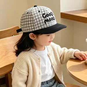 Vista detallada de la gorra de béisbol a cuadros para niños con bordido y visera negra.