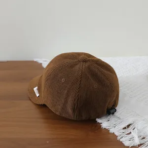 Brown corduroy baby baseball cap detail, featuring a short brim and adjustable back buckle.