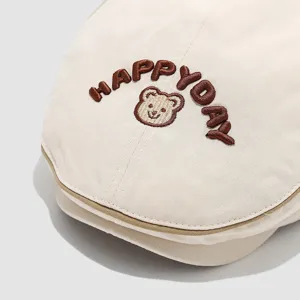 Close-up detail of cute baby beret hat with brown bear embroidery and letters.
