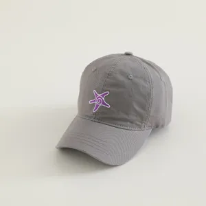 Close-up detail of grey kids baseball hat with purple embroidered starfish pattern, soft fabric.