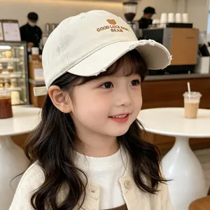 Detailed shot of kids beige baseball cap with cute bear embroidery and distressed brim.