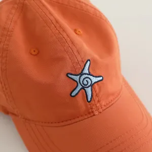 Close-up of children's orange baseball cap featuring cute blue starfish embroidery detail.
