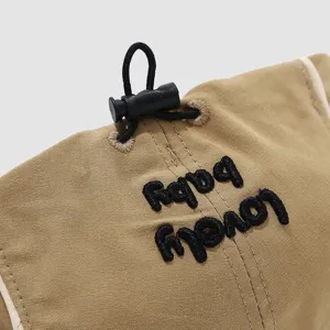Close-up detail of cute khaki baby beret hat with adjustable drawstring and lovely embroidery.
