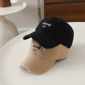 Distressed baseball cap detail showing embroidered Good lettering and smiley face on cotton fabric.