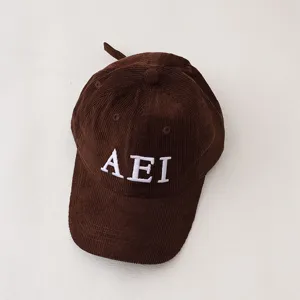 Detail shot of the brown corduroy children baseball hat featuring white AEI embroidery close up