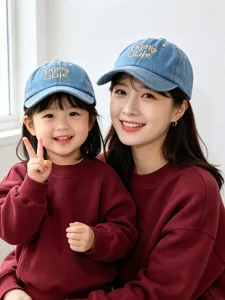 Detailed view of kids and adult denim baseball cap with cute embroidery, soft wash fabric style.