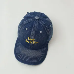 Detailed view of kids denim baseball cap, featuring cool yellow embroidery text and panels.