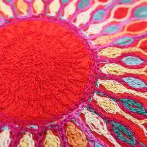 Close-up view of ethnic embroidered scarf, vibrant sunflower floral pattern texture details.