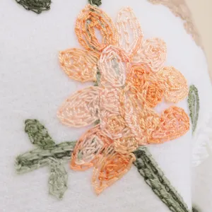 Closeup of exquisite floral embroidery on white cashmere-like winter scarf shawl detail.