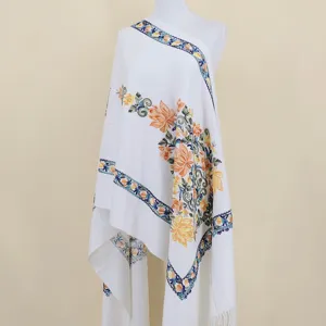 Detailed view of the white cashmere feel shawl with blue and orange floral embroidery design.