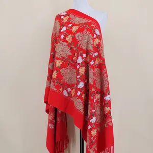 Detail view of a red embroidered floral shawl wrap with fringe, warm and festive style.