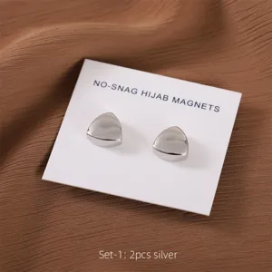 Close-up van zilveren driehoekige hijabmagneten op displaykaart, gladde metalen afwerking.