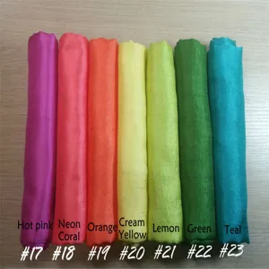 Detailed view of colorful solid scarves rolled neatly, showcasing various vibrant color options.