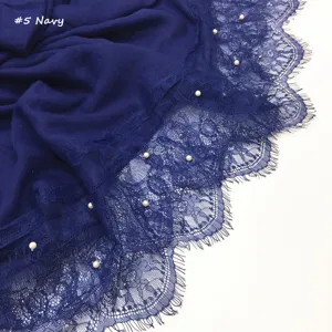 Close-up detail van de donkerblauwe sjaal met fijne kantrand en ingenaaide parels.