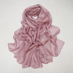 Close-up detail of soft solid color crinkled scarf texture, elegant pink fabric shawl.