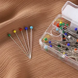 Primo piano dettagliato di spille con testa di perla colorate e scatola di posizionamento.