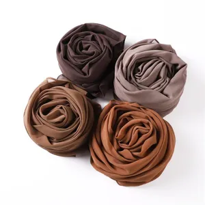 Nahaufnahme von vier gerollten Chiffonschals in eleganten Rosettenformen mit Erdtönen.